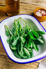 Wall Mural - Fresh green baby spinach on plate on wooden rustic table. Healthy diet, vegetarian food concept.