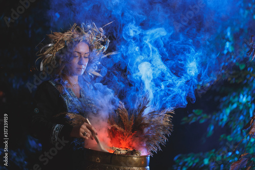 Fotografía A forest witch brews a potion holding a Voodoo doll.