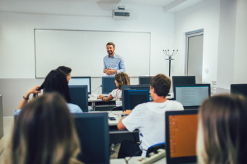 Sticker - College students sitting in a classroom, using computers during class.