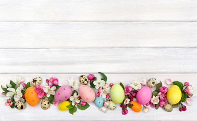 Wall Mural - easter decoration. pink flowers apple tree and colored easter eggs and quail eggs on background of w