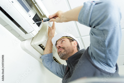 Fotomural young man cleaning air conditioning system