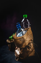 Dirty Paper Sack With Discarded Plastic Bottles Placed On Black Background