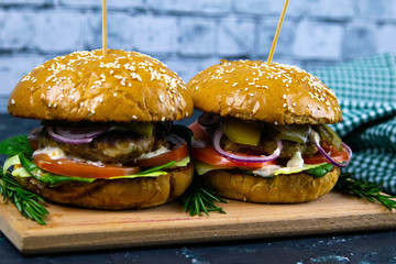 Two homemade beef burgers with mushrooms, micro greens, red onion on wooden cutting board