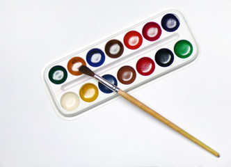 Top view of paint with a brush. A box of watercolor paints with a paint brush is isolated on a white background.