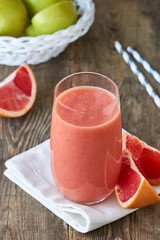 Wall Mural - Glass of grapefruit smoothie on a wooden background
