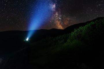 Wall Mural - bright starry sky with the milky way on the background of mountains and hiker with red tent.