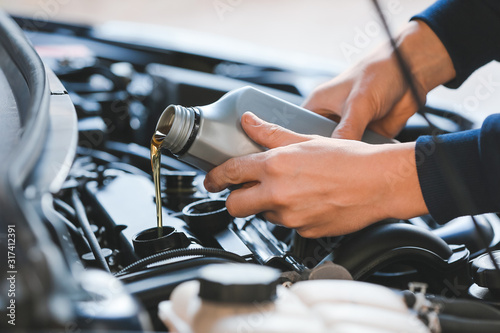 Fotomural Male mechanic refilling car oil in service center