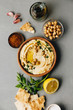 Large bowl of homemade hummus garnished with chickpeas, red sweet pepper, parsley and olive oil
