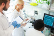 © Acronym - Scientist and students working in lab. Doctor teaching interns to make blood analyzing research. Biotechnology, chemistry, bacteriology, virology and health care concept.