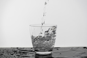 Wall Mural - Motion blur of pouring pure drinking water flow into the glass making splash of clearly bubble