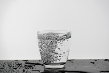 Wall Mural - Motion blur of pure drinking water in the glass with splash of clearly bubble isolated on wooden table