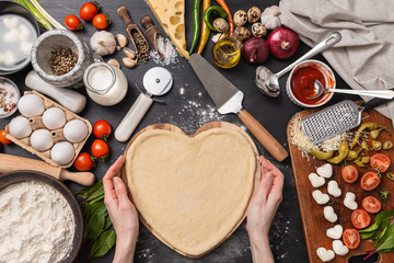 woman preparing a festive dinner for two in honor of Valentine's Day classic Italian pizza Margherita in the shape of a heart and mozzarella in the shape of a heart