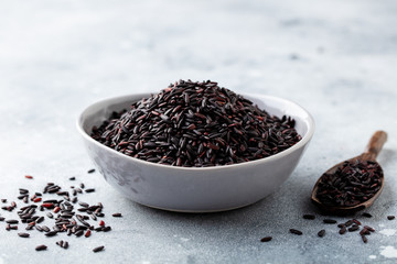 Black wild rice in a bowl. Grey stone background. Close up.