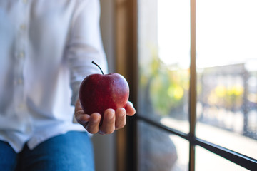 Wall Mural - Closeup image of a woman holding and giving a red apple
