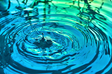 Raindrops fall on the surface of the water. The circles from the raindrops on the water surface. Abstract color background of circles on the water and falling drops.