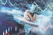 © peshkova - Financial forex graph displayed on hands taking notes background. Concept of research. Multi exposure