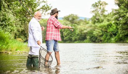 Wall Mural - Family day. Fishing team. Friends fishing. Hobby and recreation. Summer vacation. Perfect weekend. Successful catch. Relax in natural environment. Elegant bearded man and brutal hipster fishing