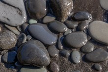 Closeup Shot Of Several Stones On The Beach Put On Black Sand