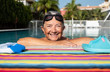 A moment of breath for the attractive senior woman who loves to swim. Large smile. Outdoor pool with blue water. Healthy activity to keep fit. Retired in a tropical place
