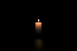 A lighted candle on a neutral black background, ideal for text application
