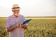 © Ivan - Smiling gray-haired senior farmer or agronomist filling out questionnaire while inspecting large organic farm. Healthy food production.