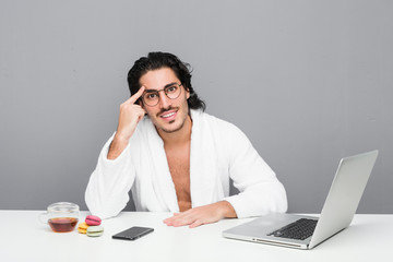 Wall Mural - Young handsome man working after a shower showing a disappointment gesture with forefinger.