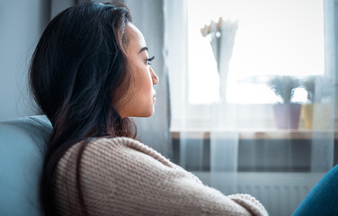 Depressed asian girl sitting on sofa at home and thinking