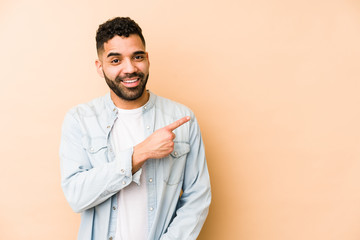 Wall Mural - Young mixed race arabic man isolated smiling and pointing aside, showing something at blank space.