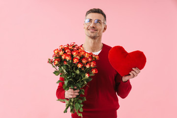 Wall Mural - Portrait of handsome caucasian man holding flowers and toy heart