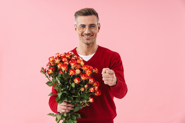 Poster - Portrait of handsome man holding flowers and pointing finger at camera