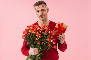 Poster - Portrait of man with kiss marks at his face holding flowers and gift box