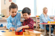 © LIGHTFIELD STUDIOS - Selective focus of kids folding educational game with teacher at background in montessori class
