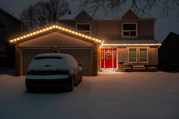 Nighttime Shot of a Detached Suburban House With a Red Door All Lit Up with Christmas Lights