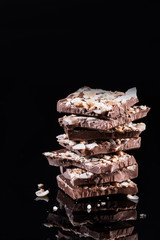 Stack of Broken Chocolate Pieces on Black Background. Copy Space. Closeup View