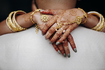 Wall Mural - Bride's hands are colored with henna, on the groom's neck, bracelets and wedding accessories