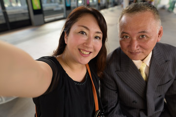 Poster - Mature Asian businessman and mature Asian woman exploring the city together