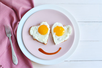 Two fried eggs on pink plate for healthy breakfast on wooden table. top view