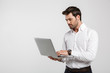© Drobot Dean - Image of young successful businessman holding and using laptop