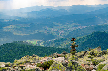 Huge stones covered with green lichen lie on the top of the mountain against the backdrop of ancient, high mountain ranges