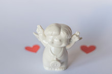 Ceramic Figurine On A Blue Background And Red Hearts In Blur . Valentine's Day. Selective Focus.