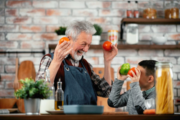 Wall Mural - Grandpa and grandson in kitchen. Grandfather and his grandchild having fun while cooking. 