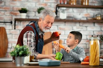 Wall Mural - Grandpa and grandson in kitchen. Grandfather and his grandchild having fun while cooking. 