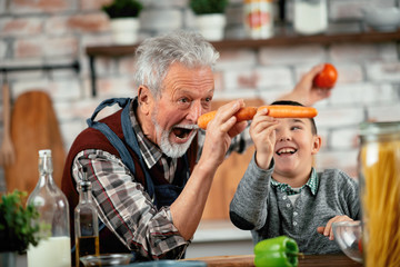 Wall Mural - Grandpa and grandson in kitchen. Grandfather and his grandchild having fun while cooking. 