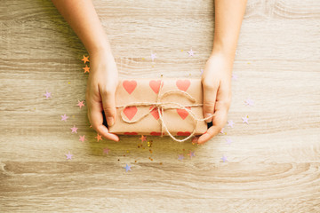 Wall Mural - Gift box wrapped with craft brown paper with hearts in female hands