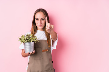 Wall Mural - Young gardener caucasian woman isolated showing number one with finger.