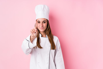 Wall Mural - Young caucasian chef woman isolated showing number one with finger.