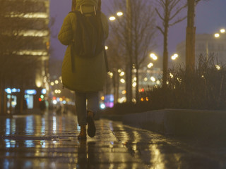 Wall Mural - Defocused photography of colorful street lights in night. Impressionism style. Gold lights with black background. Silhouette of young woman with backpack. Back / rear view. Suitable as background