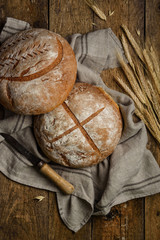 Homemade wheat rye bread on an old wooden table. Two loaves of round bread on a linen cloth. Top view