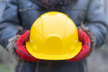 Architect Or Industrial Worker Holding In Red Gloves Yellow Hard Hat. Safety Work Health First Construction Industry Background. Protective Equipment Concept.