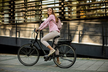 Young Woman Riding E Bike In Urban Enviroment